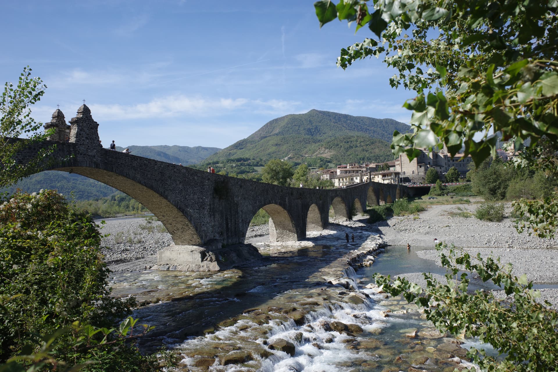 Ponte Gobbo med sina ojämna stenvalv över Trebbia, med Bobbio och berget bakom
